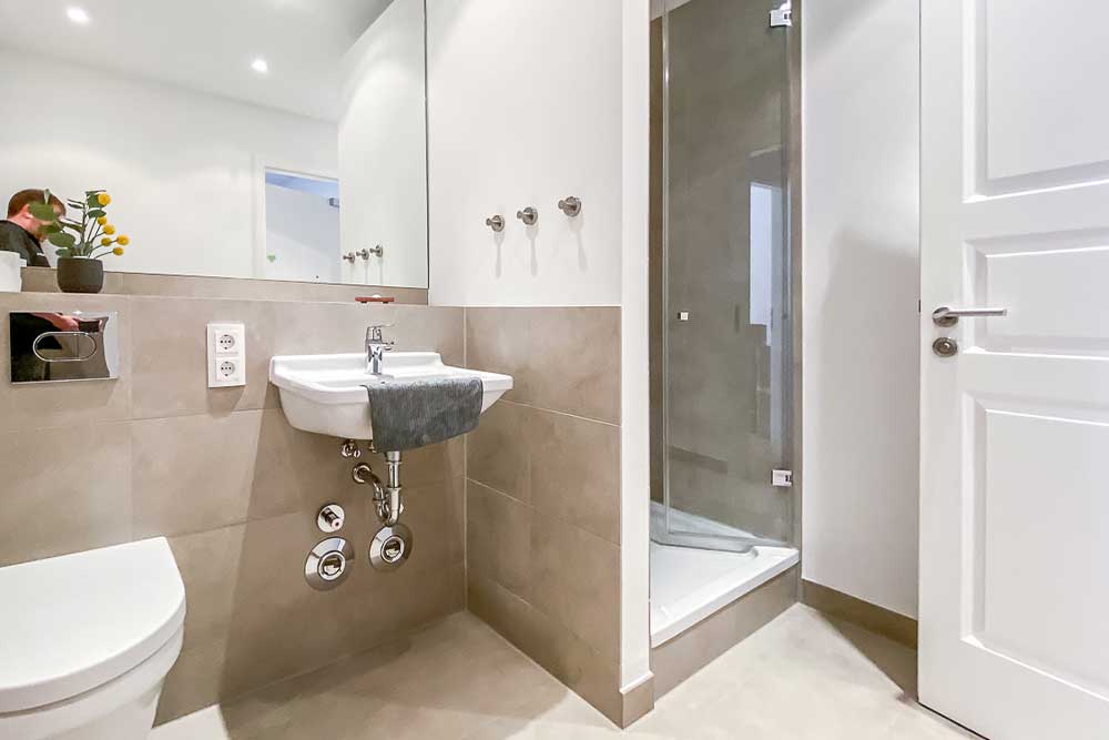 photographer can be seen in the mirror and in the toilet flush despite the flower pot, reflection from the hallway in the shower door